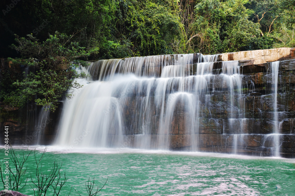 The beautiful waterfall in forrest down to emerald green lake.