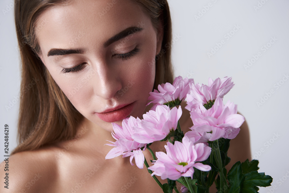 Charming young woman holding beautiful pink flowers