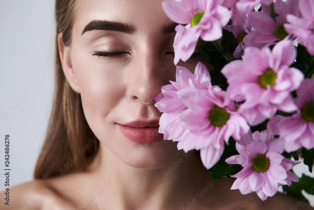 Attractive young woman enjoying aroma of beautiful pink flowers Attractive young woman enjoying aroma of beautiful pink flowers