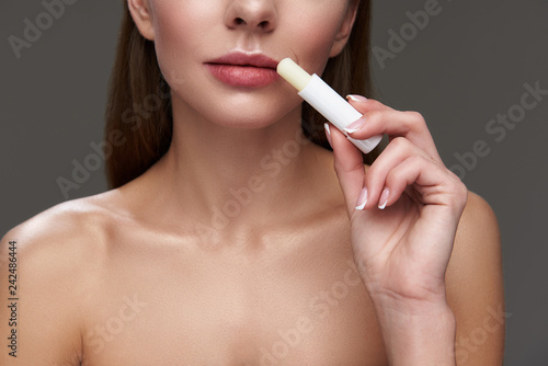 Young lady with beautiful lips using hygienic lipstick