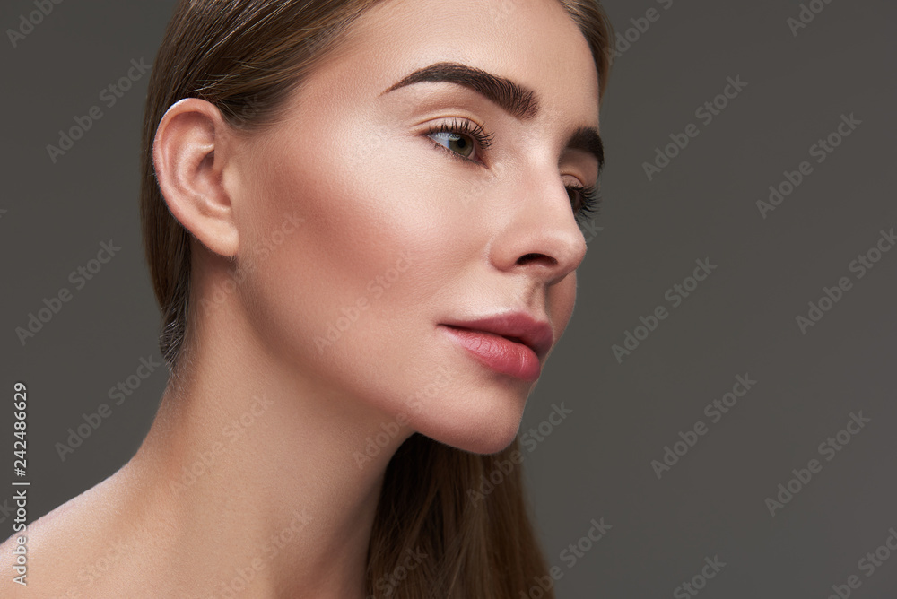 Fototapeta premium Charming young lady with perfect skin posing against gray background