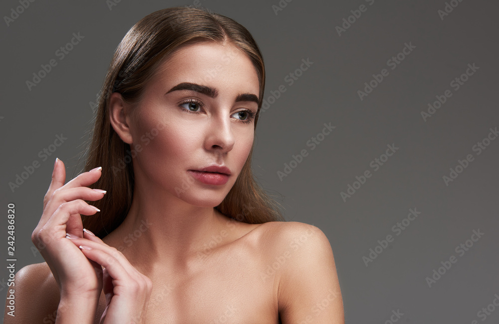Charming young lady standing against gray background Charming young lady standing against gray background