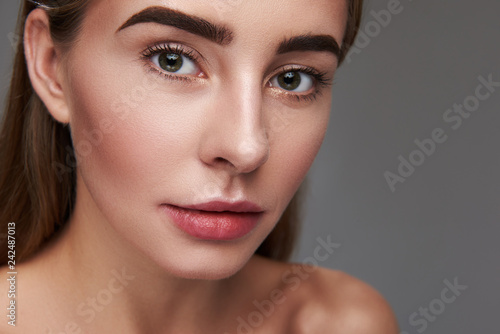 Attractive young woman with natural makeup isolated on gray background
