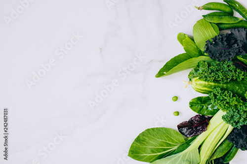 Frame of fresh green vegetables on a marble background, copy space, flay lay, top view