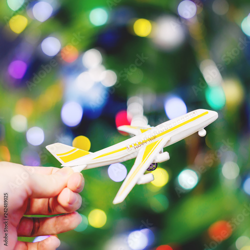 Toy plane in the palm of your hand. Inscription on the plane happy trip. Abstract colorful background. Blue, purple, green, red colors. © NATALYA