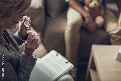 Calm psychologist holding glasses while sitting with her notes