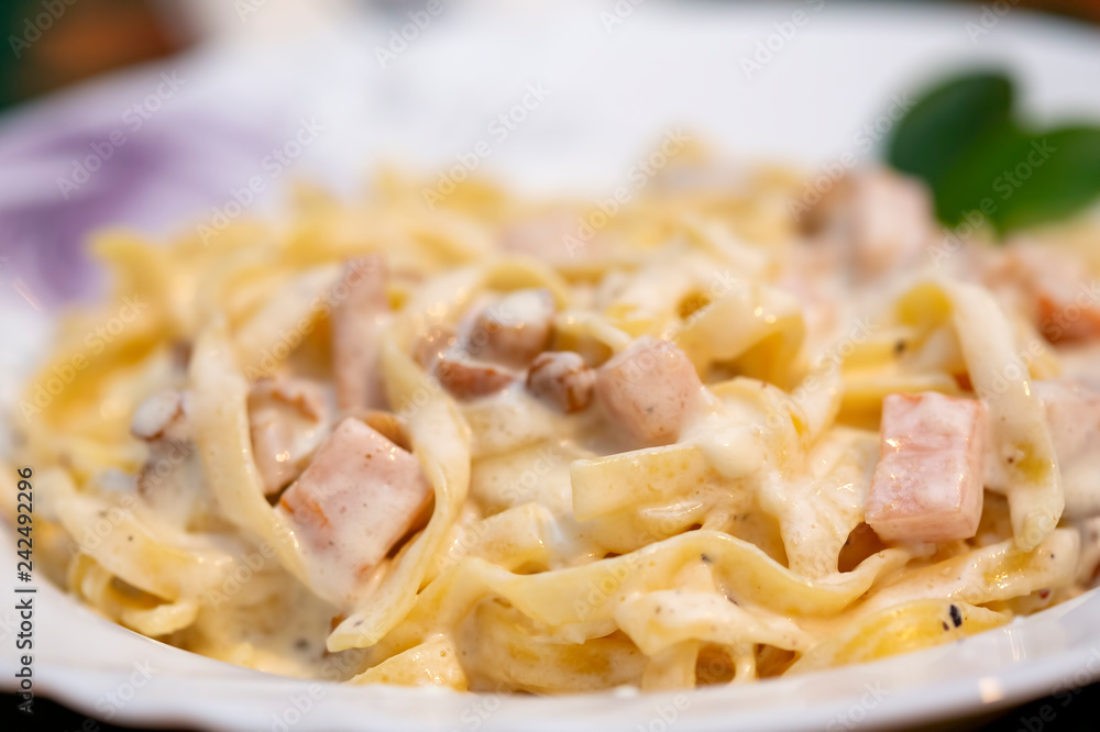 Tagliatelle pasta with cream, meat and mushrooms on the plate