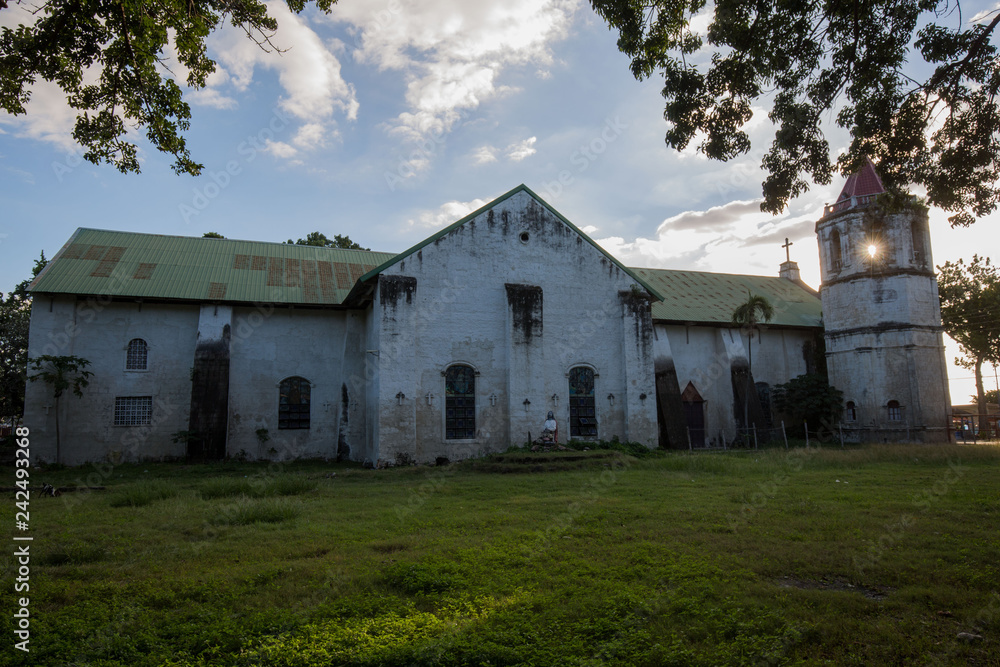 old Spanish Church in Philippines in a sunlight with white clouds and sunbeams on church spire 