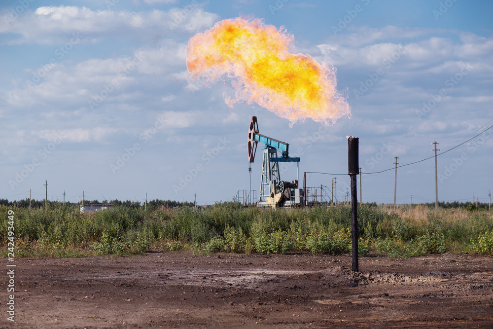 Obraz premium Oil pumpjack and gas torch on oil production