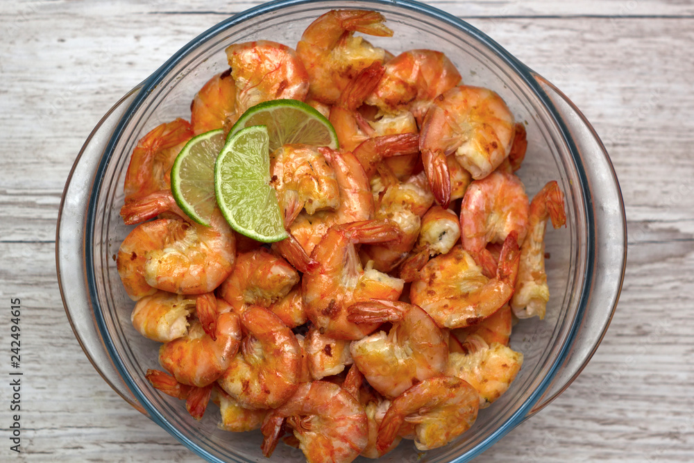 fried roasted shrimps in plate with lime pils in a big glass plate on grey background fried roasted shrimps in plate with lime pils in a big glass plate on grey background
