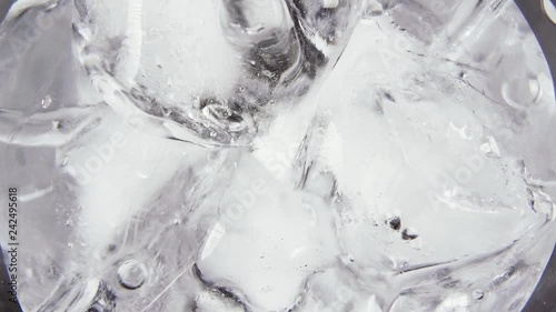 Slow motion pour a clear alcoholic drink vodka in a glass of ice top view