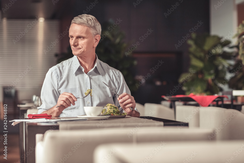 Calm old man eating a salad in a restaurant Calm old man eating a salad in a restaurant