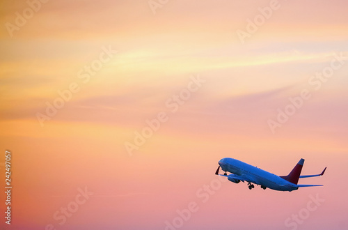 Passenger plane taking off over the evening orange sky.