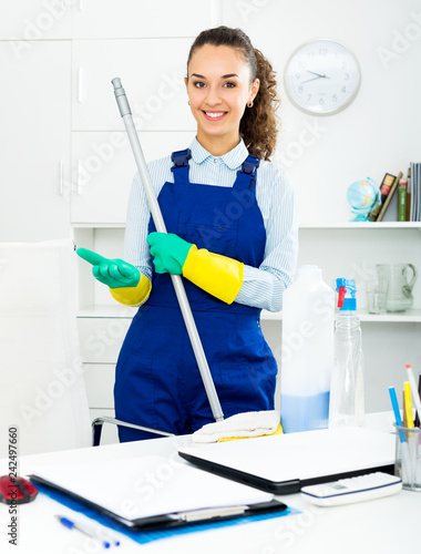 Woman with supplies cleaning in office photo