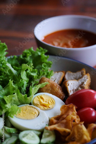 Muslim salad with sauce on wood table and have some space for write wording, delicious appetizer with many kinds of vegetable, green leaf lettuce, onion, boiled egg, tofu, high nutrition