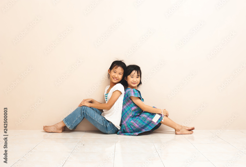 Cute asian siblings sit and touch each other with their backs. Lovely sincere emotions from childhood. Cute asian siblings sit and touch each other with their backs. Lovely sincere emotions from childhood.