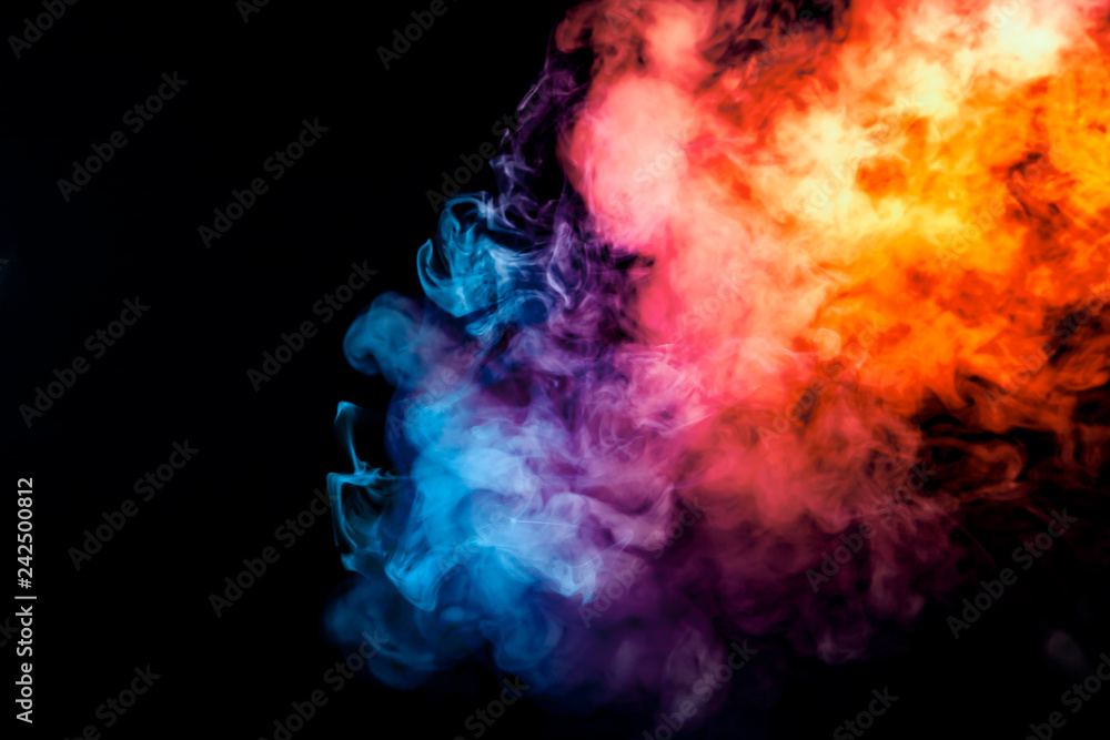 Fototapeta premium The thick smoke exhaled from the vape is highlighted by a blue-violet orange color like a rainbow against a black background dynamically in a rising column of steam.