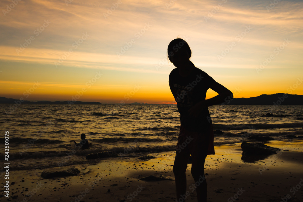 Child playing with sun is hiding the beach edge with orange sky