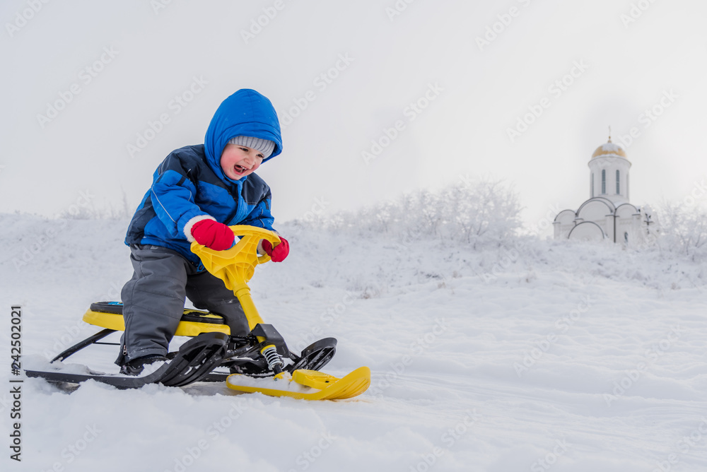 little child riding a snow scooter in winter little child riding a snow scooter in winter