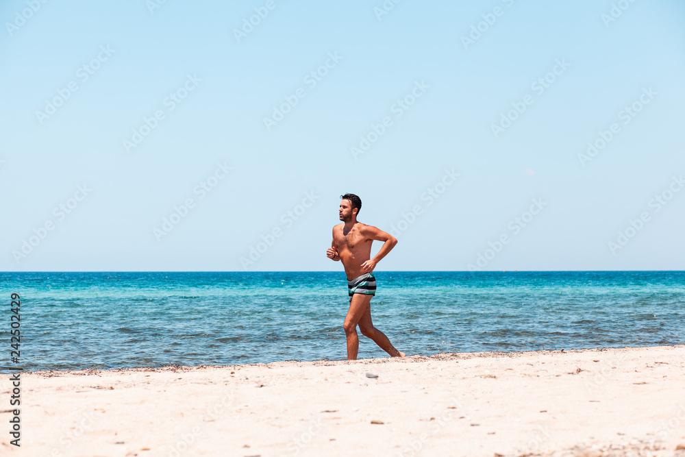 Young handsome man running on the beach Young handsome man running on the beach