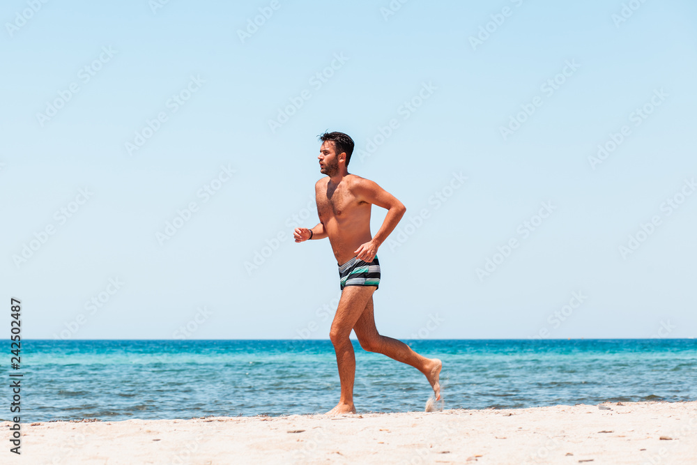 Young handsome man running on the beach Young handsome man running on the beach