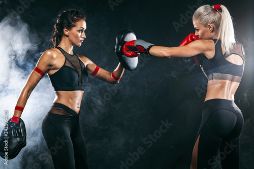 Two women athlete and boxer trainging before fight on black background. Sport and boxing concept.