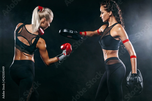 Two women athlete and boxer trainging before fight on black background. Sport and boxing concept.