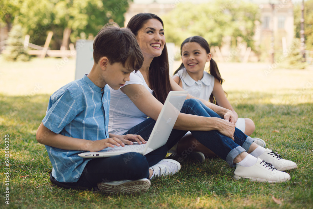 Teacher and two young students use laptop in park Teacher and two young students use laptop in park