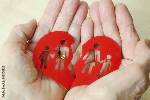 Woman hands holding paper broken heart with a family - Divorce and broken family concept photo