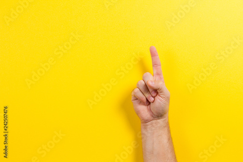 Man hand showing one finger on yellow background photo
