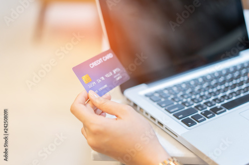 Asian Woman's hands holding a credit card and using smart phone and laptop tablets for online shopping,she smiling ,looking her credit-card shop Online payment and retail concept,Internet Theft alert
