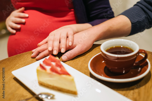 Pregnant woman with husband relax in cafe and drink coffee