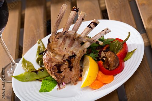 Lamb carre with vegetables and greens photo