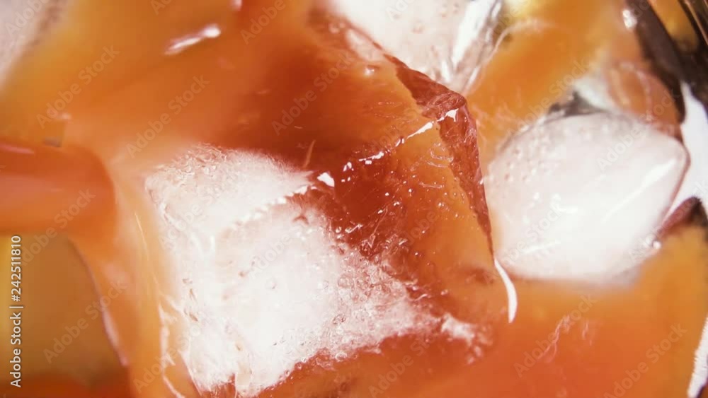 Tomato juice pour into a glass with ice cubes top view