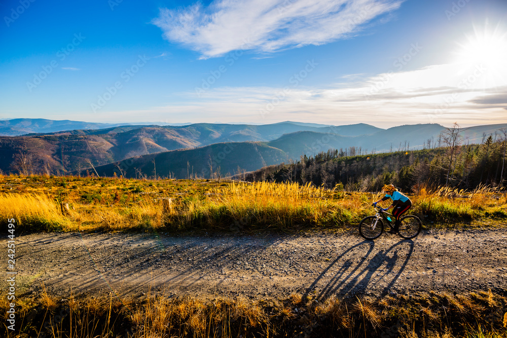 Plakat Cycling woman riding on bike in autumn mountains forest landscape. Woman cycling MTB flow trail track. Outdoor sport activity.