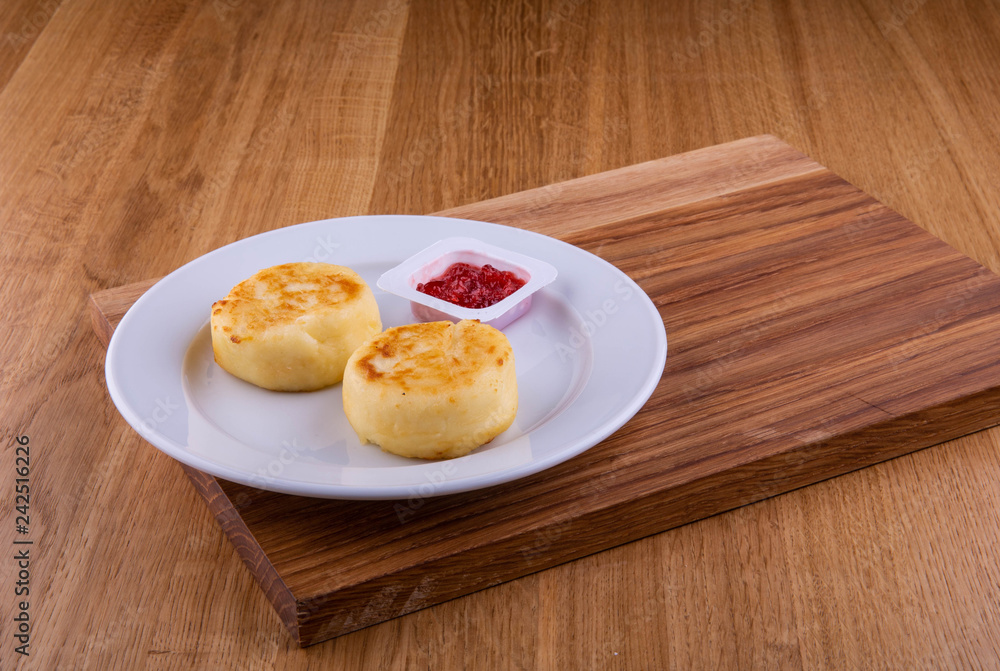 Strawberry jam with cheesecakes in a plate on a board Strawberry jam with cheesecakes in a plate on a board