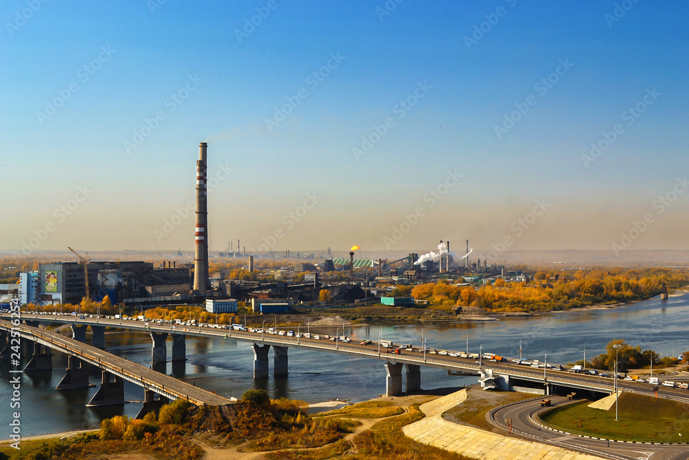 Obraz premium Kemerovo, Russia, 09.21.2011: Kuznetsky Bridge with transport, polluting the atmosphere of a plant on the river bank