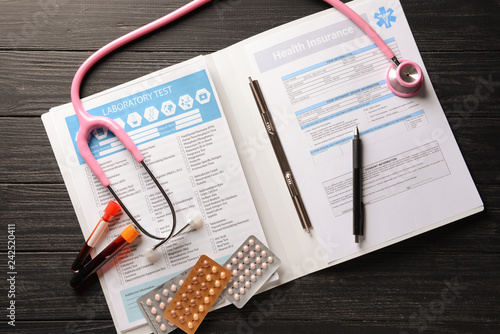 Medical documents, stethoscope, pills and test-tubes with blood on wooden table