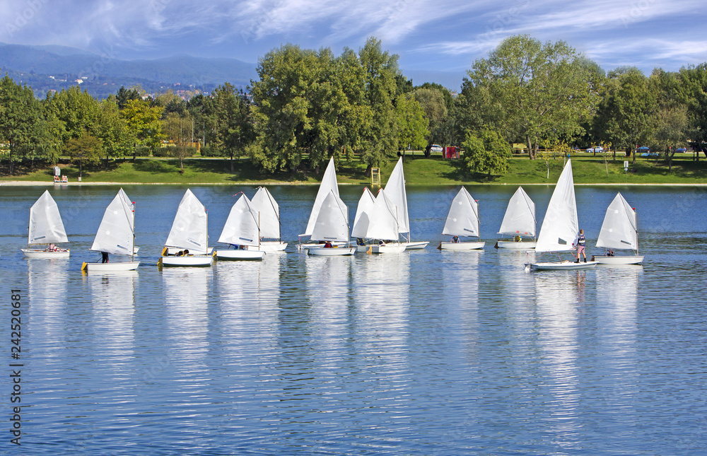 Fototapeta premium The small sailing ships regatta on the blue lake