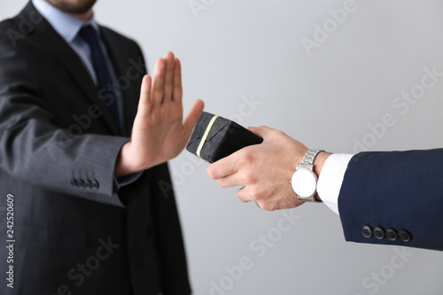 Businessman refusing to take bribe on light background. Concept of corruption photo