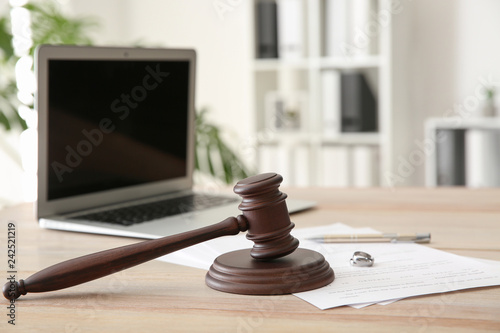 Rings with decree of divorce and judge gavel on table photo