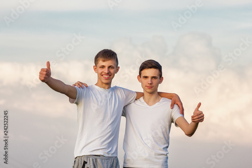 two brother guys stand against the sky happy