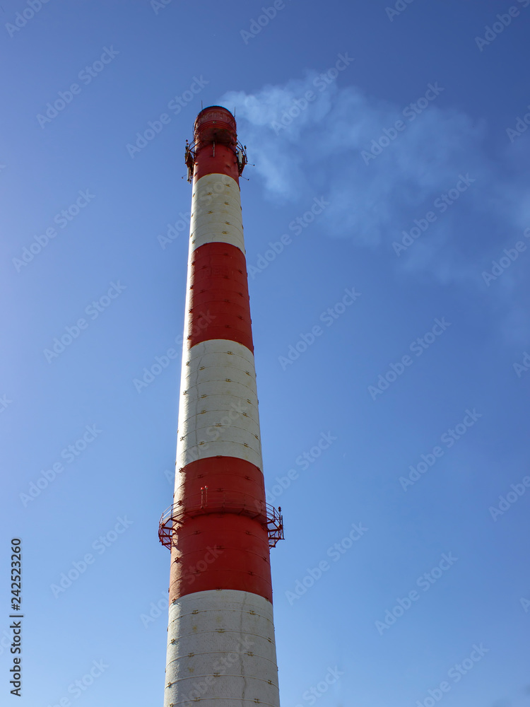 Smoke from a factory chimney against a blue sky. Vertical view. Smoke from a factory chimney against a blue sky. Vertical view.