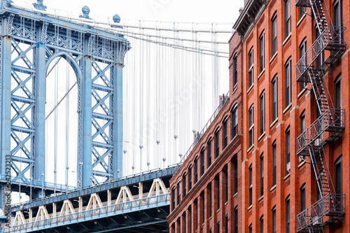 Fototapeta Naklejka Na Ścianę i Meble -  Bridge and brick industrial buildings. The famous suspension Manhattan Bridge photographed from DUMBO district in Brooklyn, New York City.