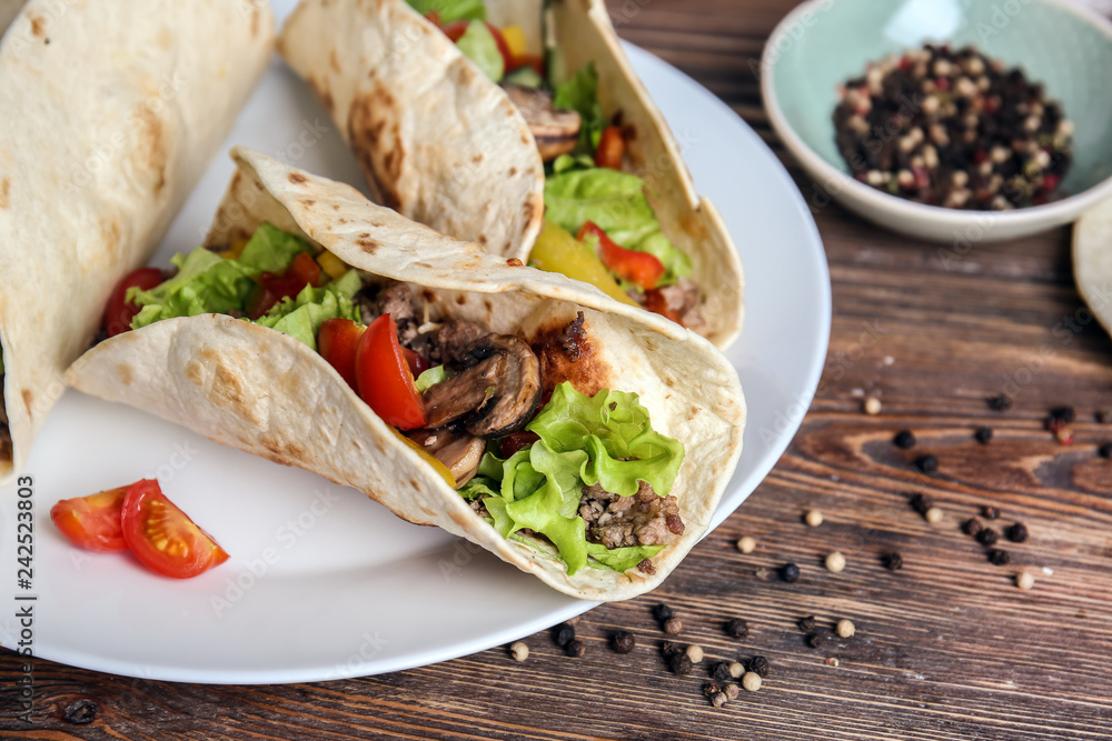 Plate with tasty tacos on wooden table Plate with tasty tacos on wooden table