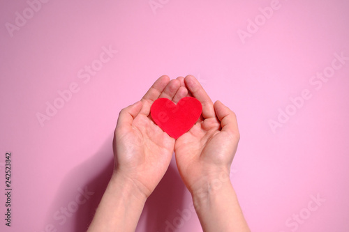 Heart in hands on a pink background. Valentine's Day