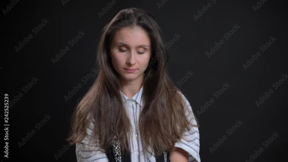 Portrait of young caucasian long-haired woman modestly watching into camera on black background. Portrait of young caucasian long-haired woman modestly watching into camera on black background.