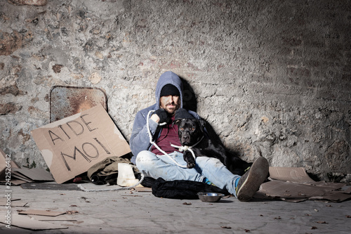 Clochard man with his dog sitting on the street