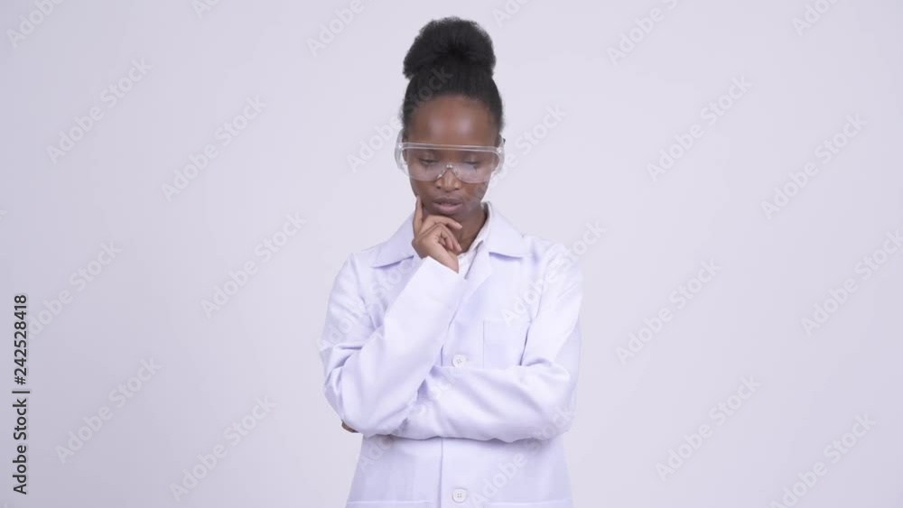 Young African woman doctor with protective glasses thinking and looking down Young African woman doctor with protective glasses thinking and looking down