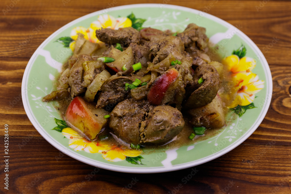 Stewed chicken liver with apple and onion on wooden table Stewed chicken liver with apple and onion on wooden table